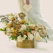 Aurelia, a luxury flower arrangement of white garden roses, saffina chrysanthemums, lisianthus, and gold painted anthurium leaves in a round TWIGS Gold box, with matching gift card.