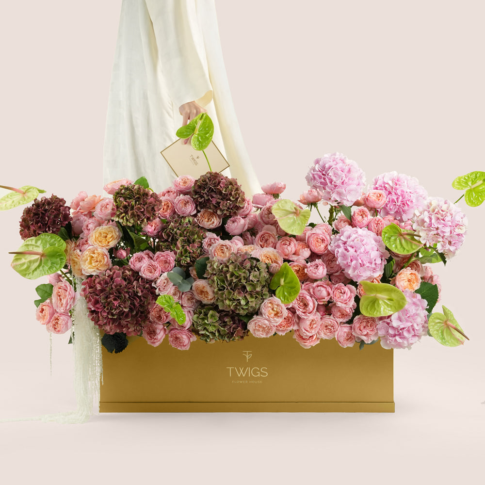 Isadora Royale, a luxury TWIGS Gold Garden box arrangement of pink and burgundy hydrangeas, garden roses, and green anthurium leaves.