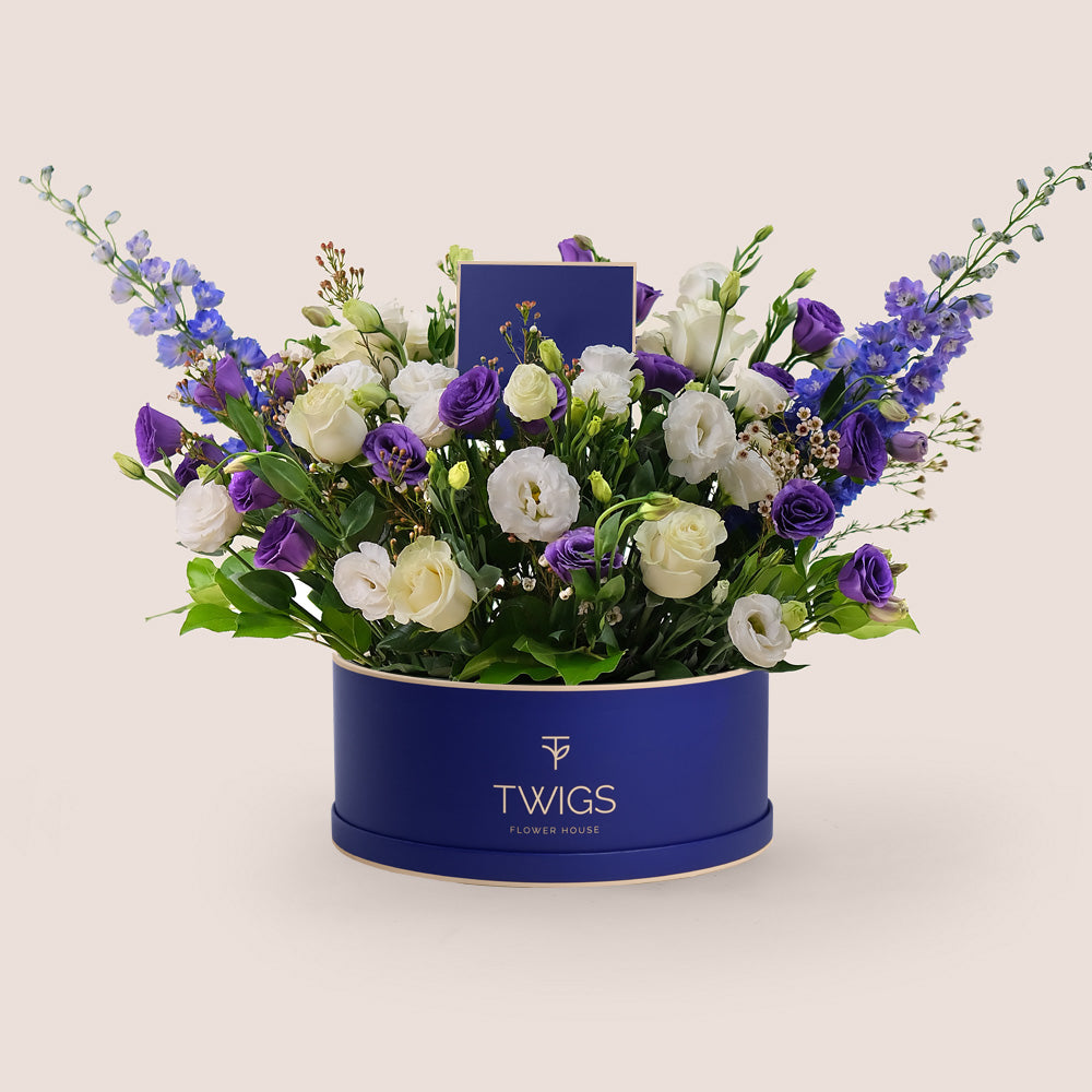 A luxurious mix of purple lisianthus, purple delphiniums, white lisianthus, and Mondial garden roses