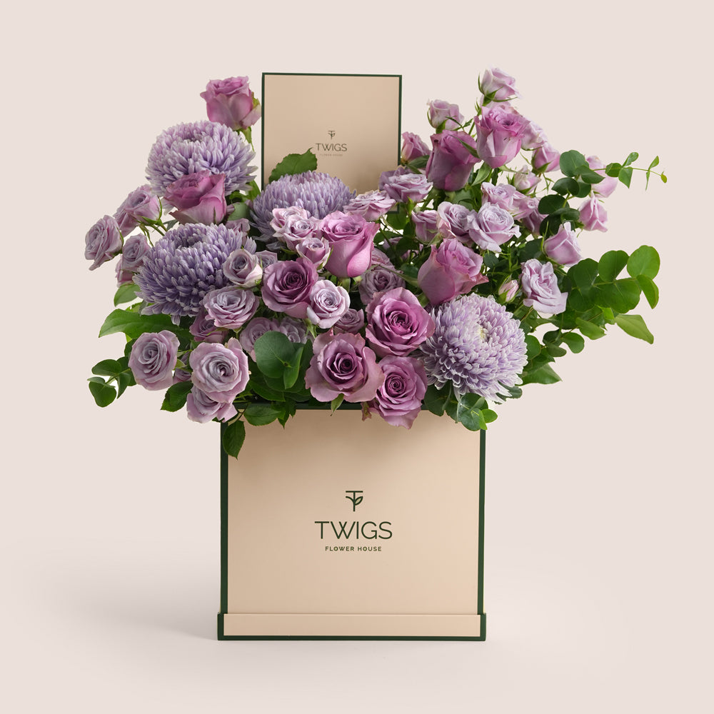Purple roses and lilac chrysanthemums in shades of lavender arranged in a beige TWIGS Flower House tall box