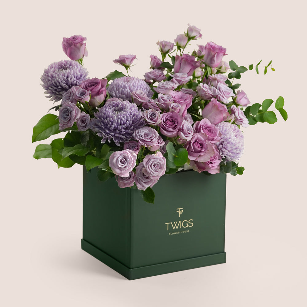 Purple roses and lilac chrysanthemums in shades of lavender arranged in a dark green TWIGS Flower House tall box