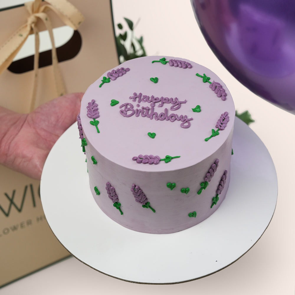 Purple birthday cake with lavender decorations on a white plate.