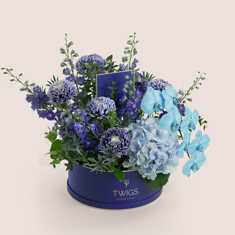 Blue Hour Grande — blue delphiniums, chrysanthemums, hydrangeas and phalaenopsis orchids in a TWIGS navy round box, Father's Day flower arrangement Abu Dhabi
