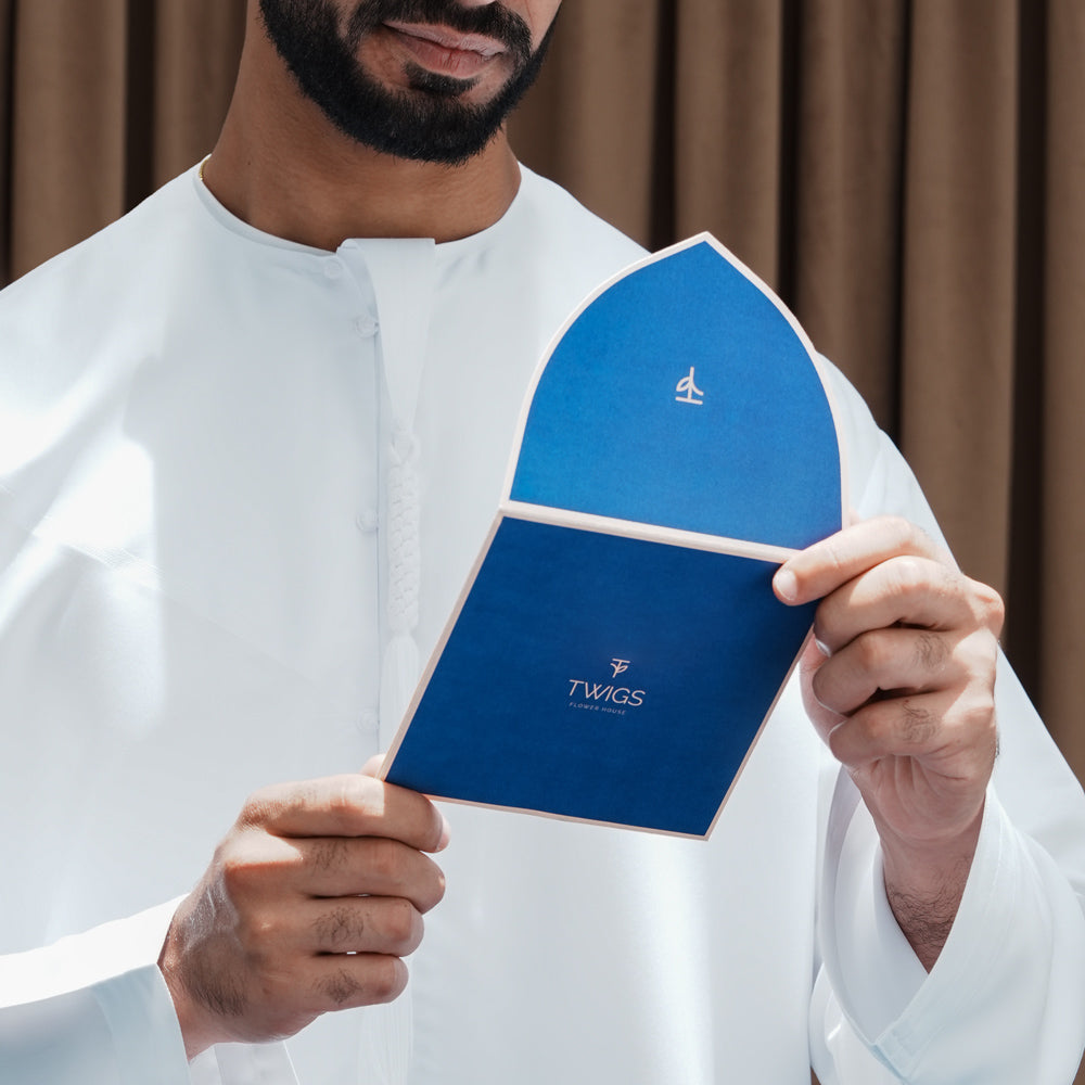 Man holding a blue product packaging with 'TWIGS' branding against a brown curtain background