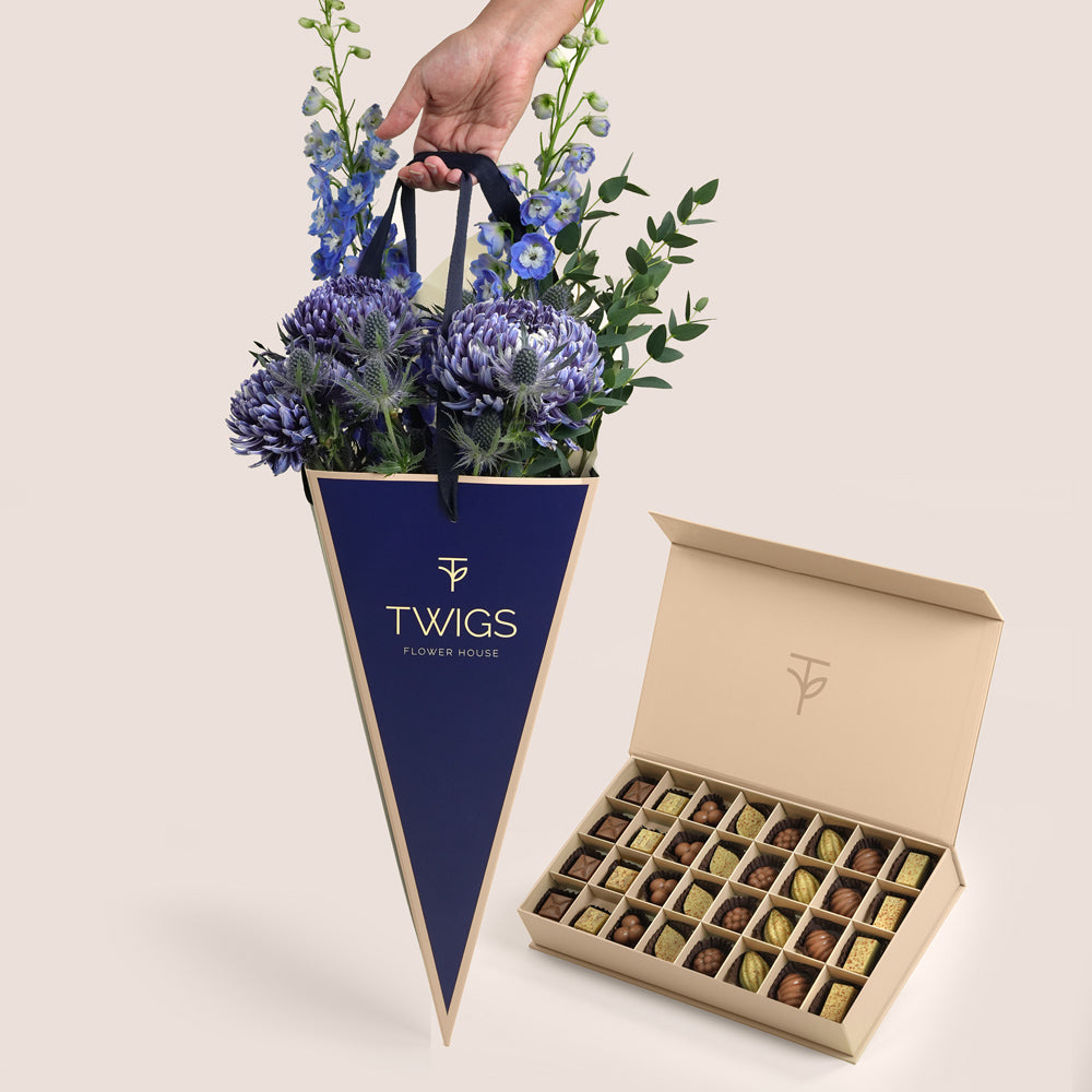 Indigo Carry & Chocolate — blue delphiniums, chrysanthemums and eryngiums in a TWIGS navy cone carry bag alongside TWIGS signature chocolate box, Father's Day gift Dubai