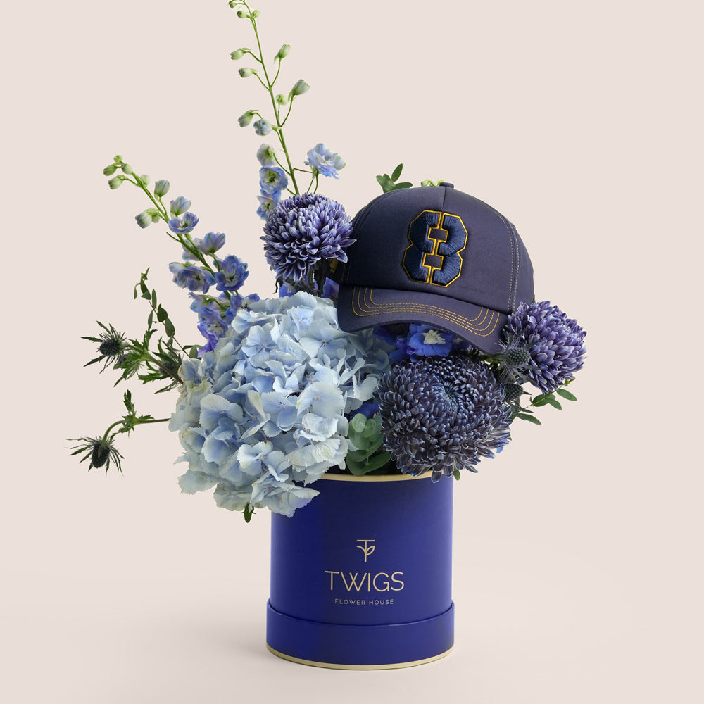 Blue Dusk & Code 8 — blue hydrangeas, delphiniums and chrysanthemums in a TWIGS navy round box with Code 8 baseball cap, Father's Day gift Dubai