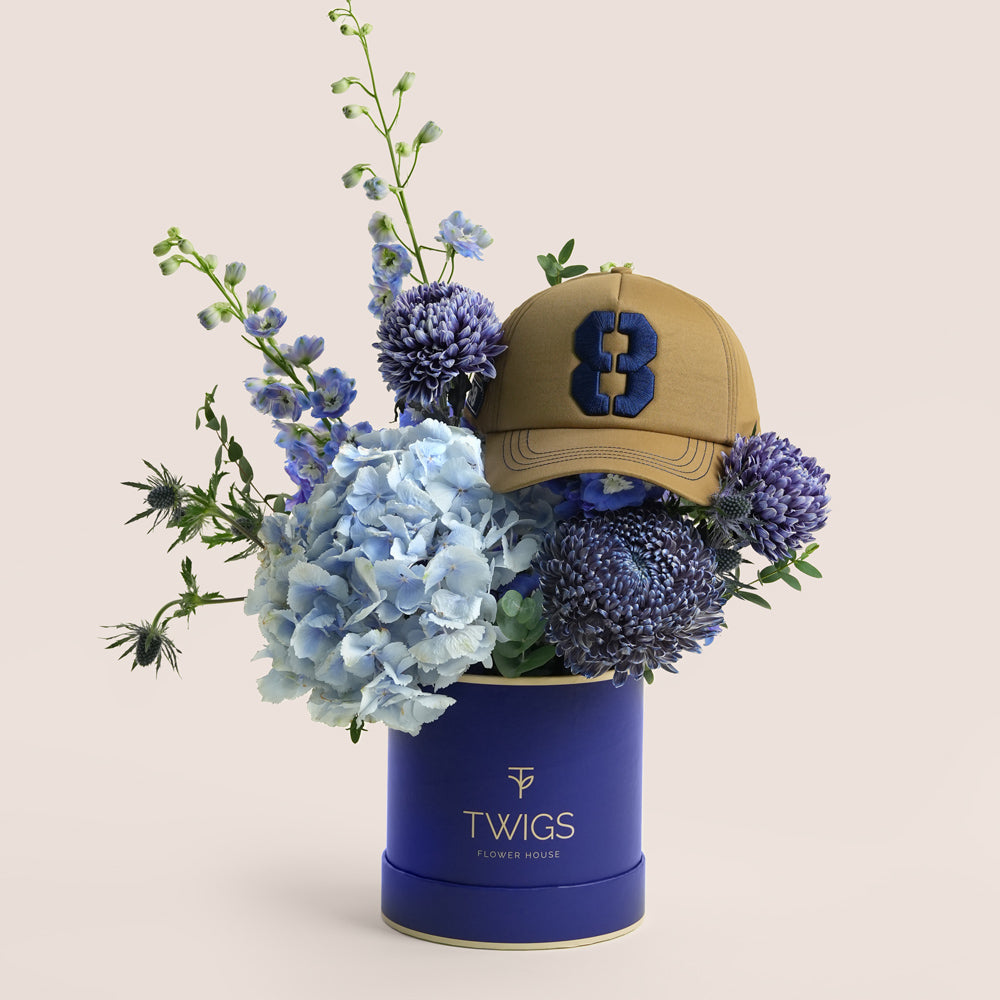 Blue Dusk & Code 8 — blue hydrangeas, delphiniums and chrysanthemums in a TWIGS navy round box with Code 8 baseball cap, Father's Day gift UAE
