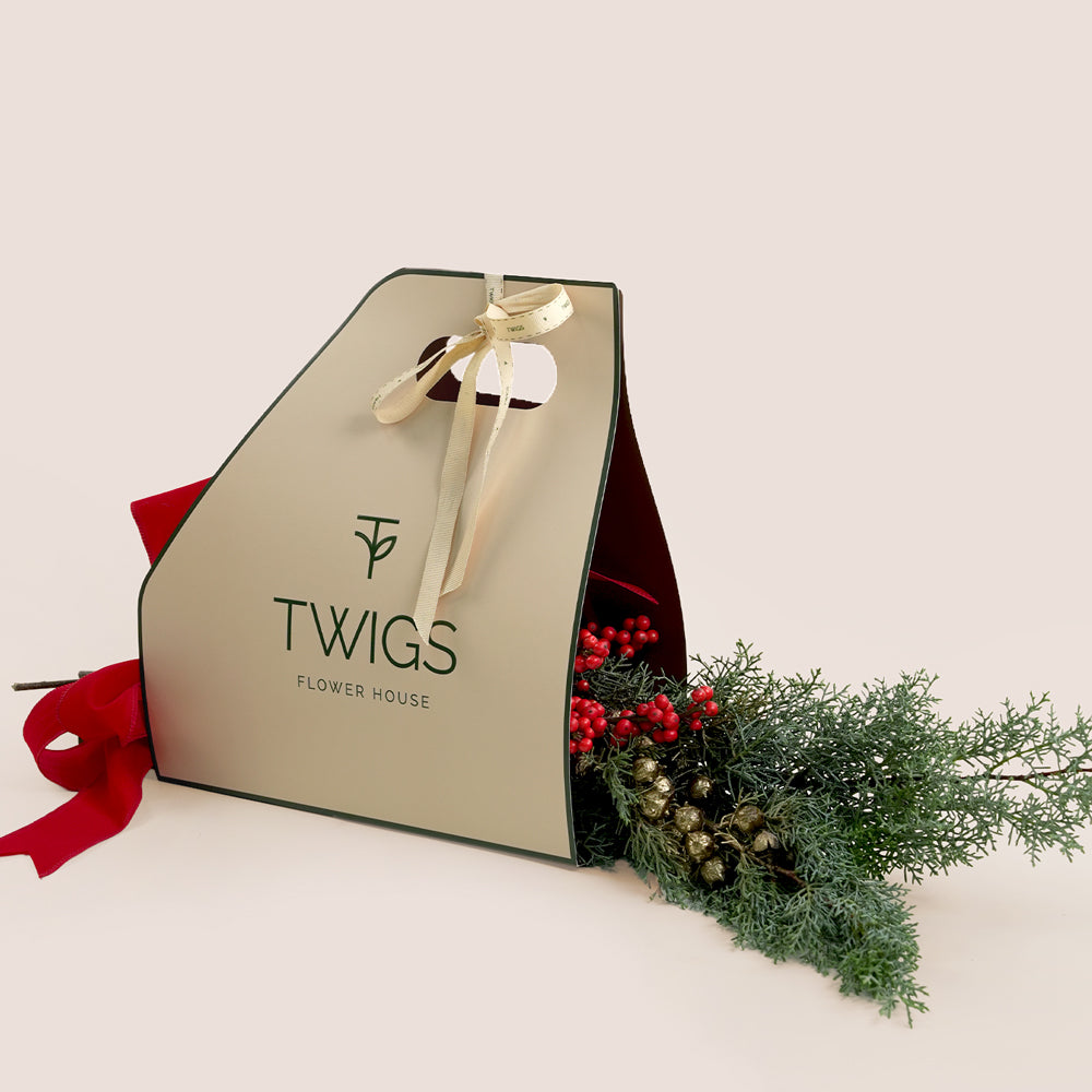 Gift bag with a bow and floral arrangement on a white background, featuring the brand 'TWIGS Flower House'.