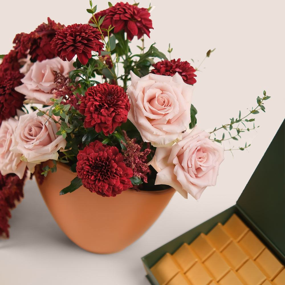 Manar’s Choice – Burgundy & Quicksand Roses in Coral Vase with Premium Belgian Chocolate