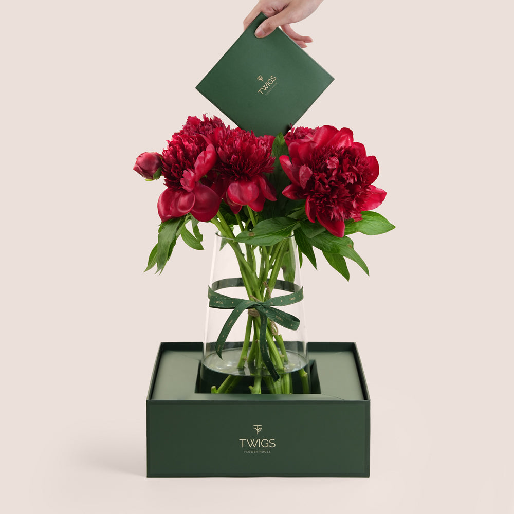 Deep red peony vase arrangement in TWIGS forest green box with message card — same-day Eid flowers UAE