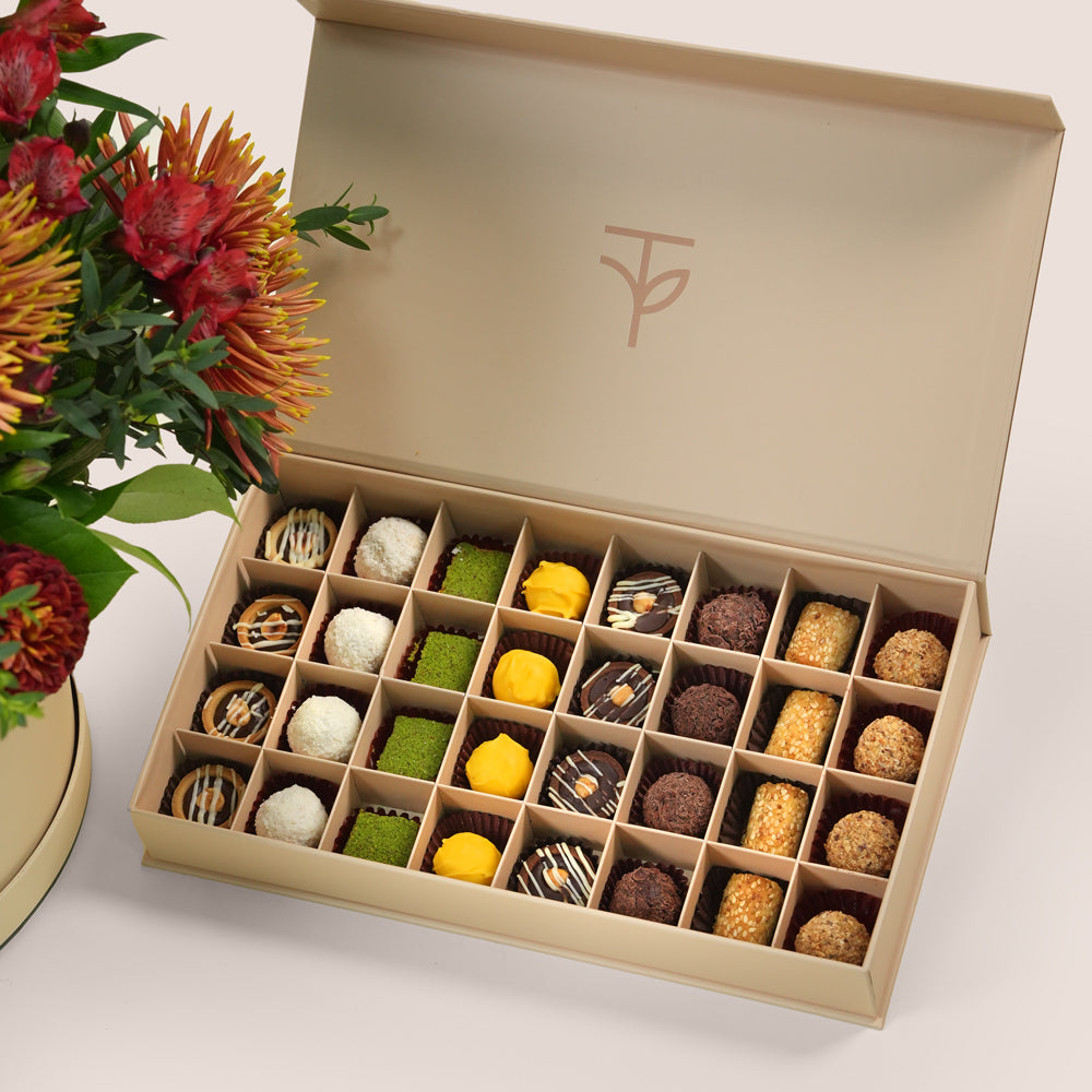 Ruby Eid flower arrangement in grande round box with premium truffles and petite fours gift box Dubai