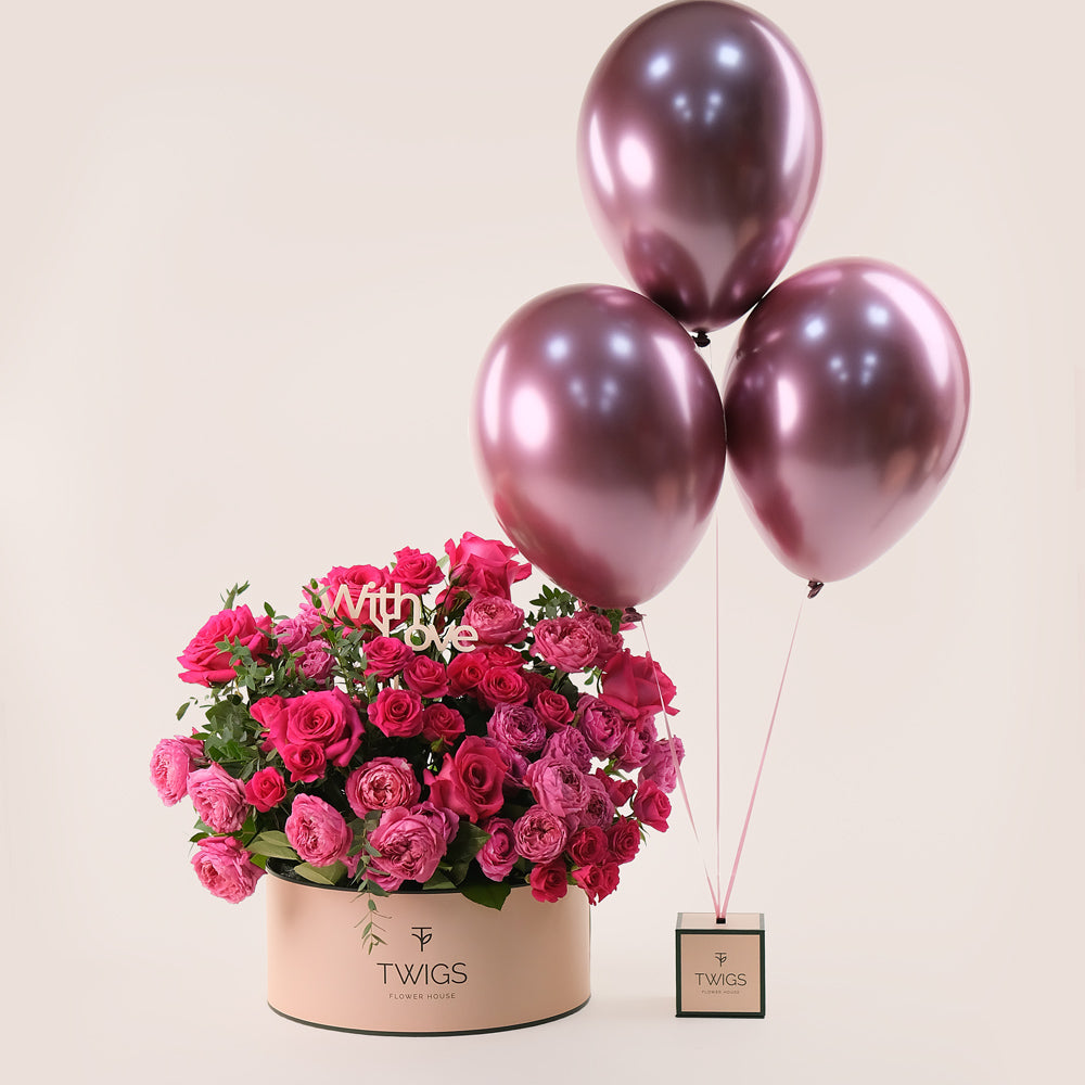 Fuchsia and Juliet cerise roses in TWIGS Grande Cylinder box with With Love topper and fuchsia chrome balloons Dubai