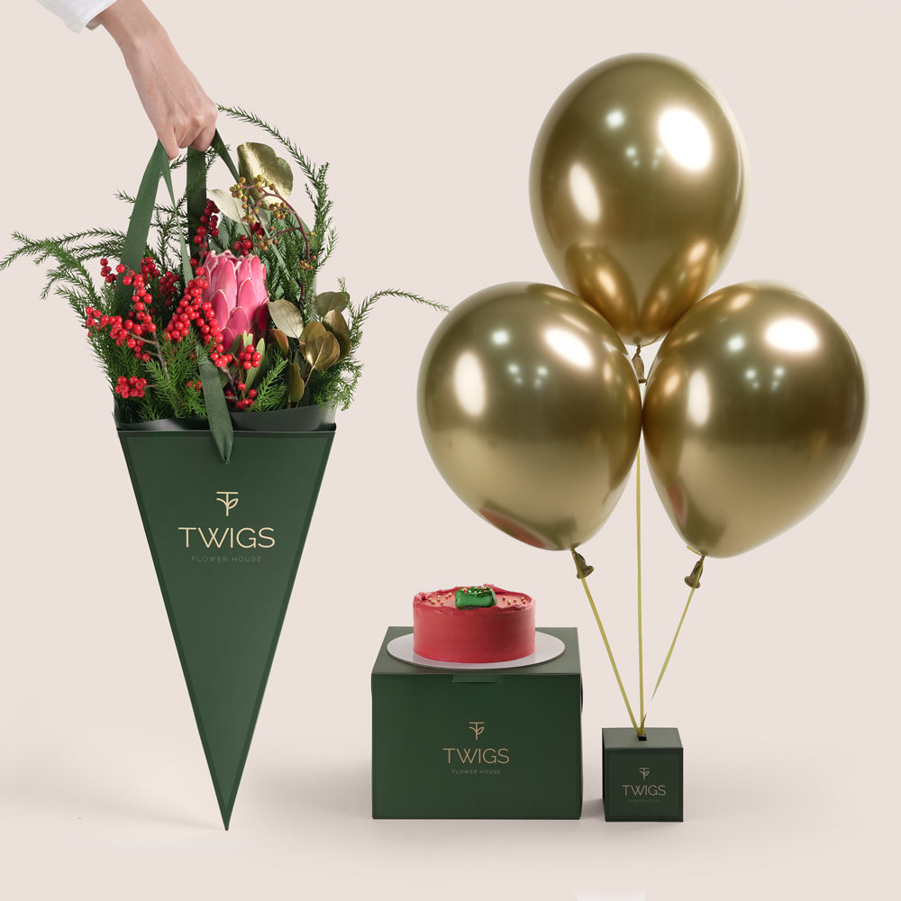 Luxury Christmas gift TWIGS cone bag with a bouquet of red roses and festive pine foliage, a small red holiday cake, and three metallic gold balloons