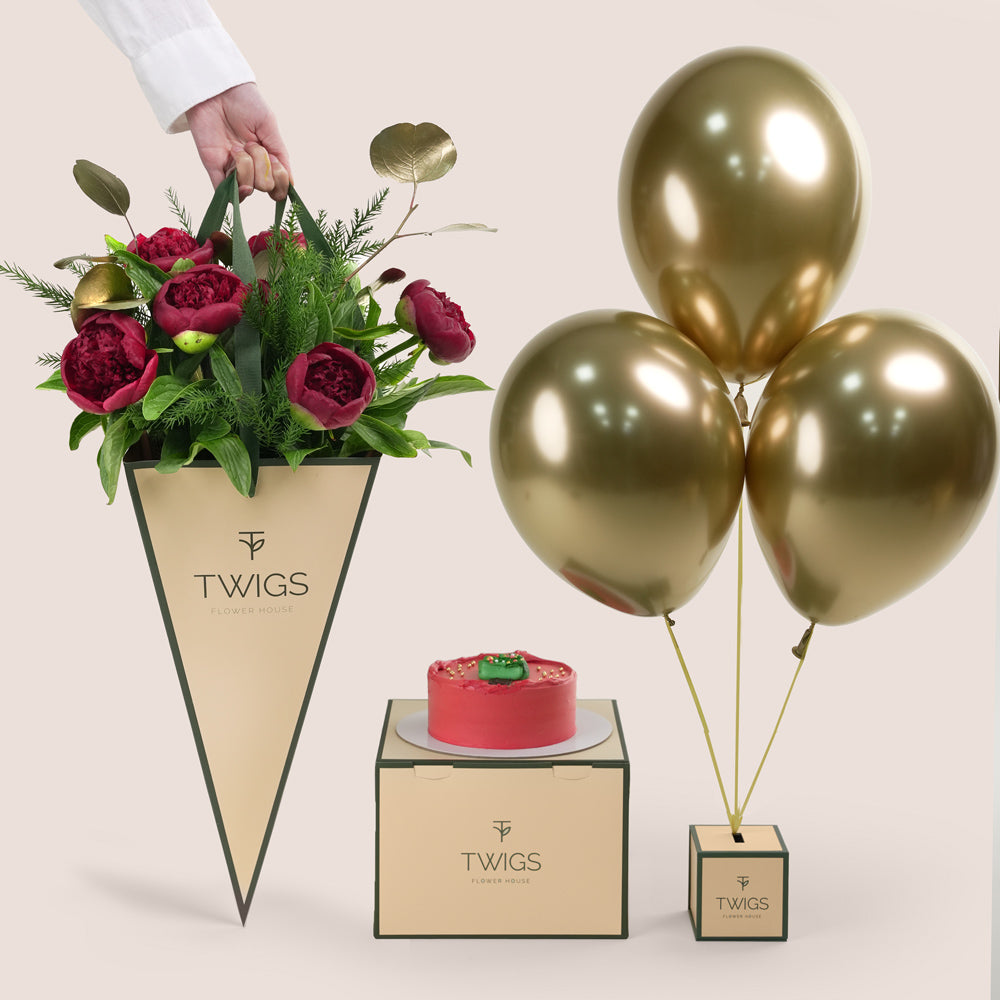 A beautiful festive flower bunch featuring a vibrant red Christmas flower arrangement red peonies 
placed beside a decorated cake