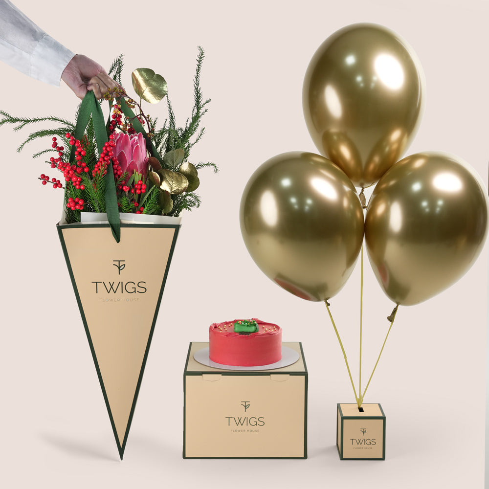 Luxury Christmas gift TWIGS cone bag with a bouquet of red roses and festive pine foliage, a small red holiday cake, and three metallic gold balloons