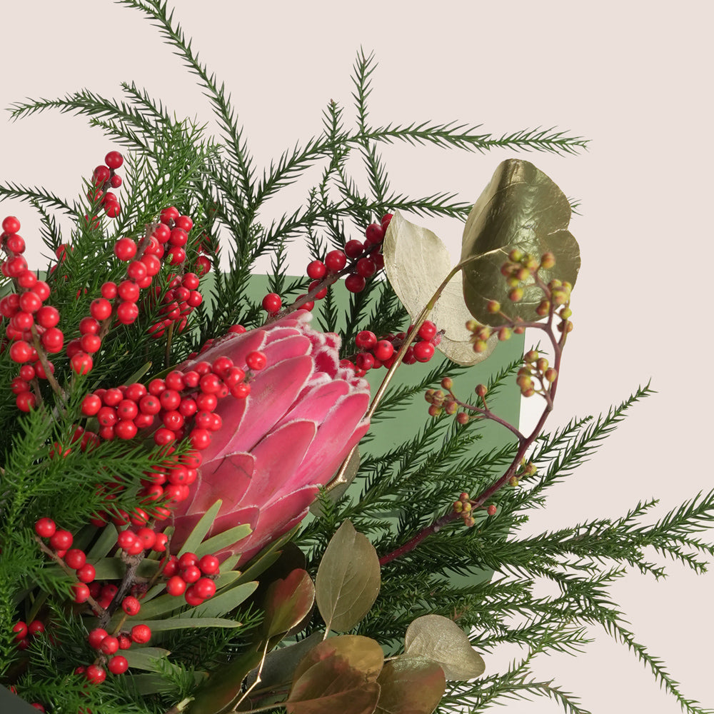 A beautiful festive flower bunch featuring a vibrant red Christmas flower arrangement placed beside a decorated cake