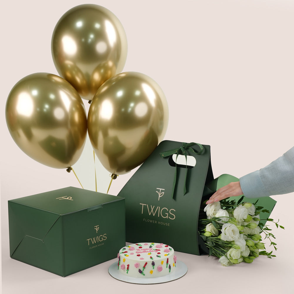 Gold balloons, cake, and bouquet of flowers for birthday