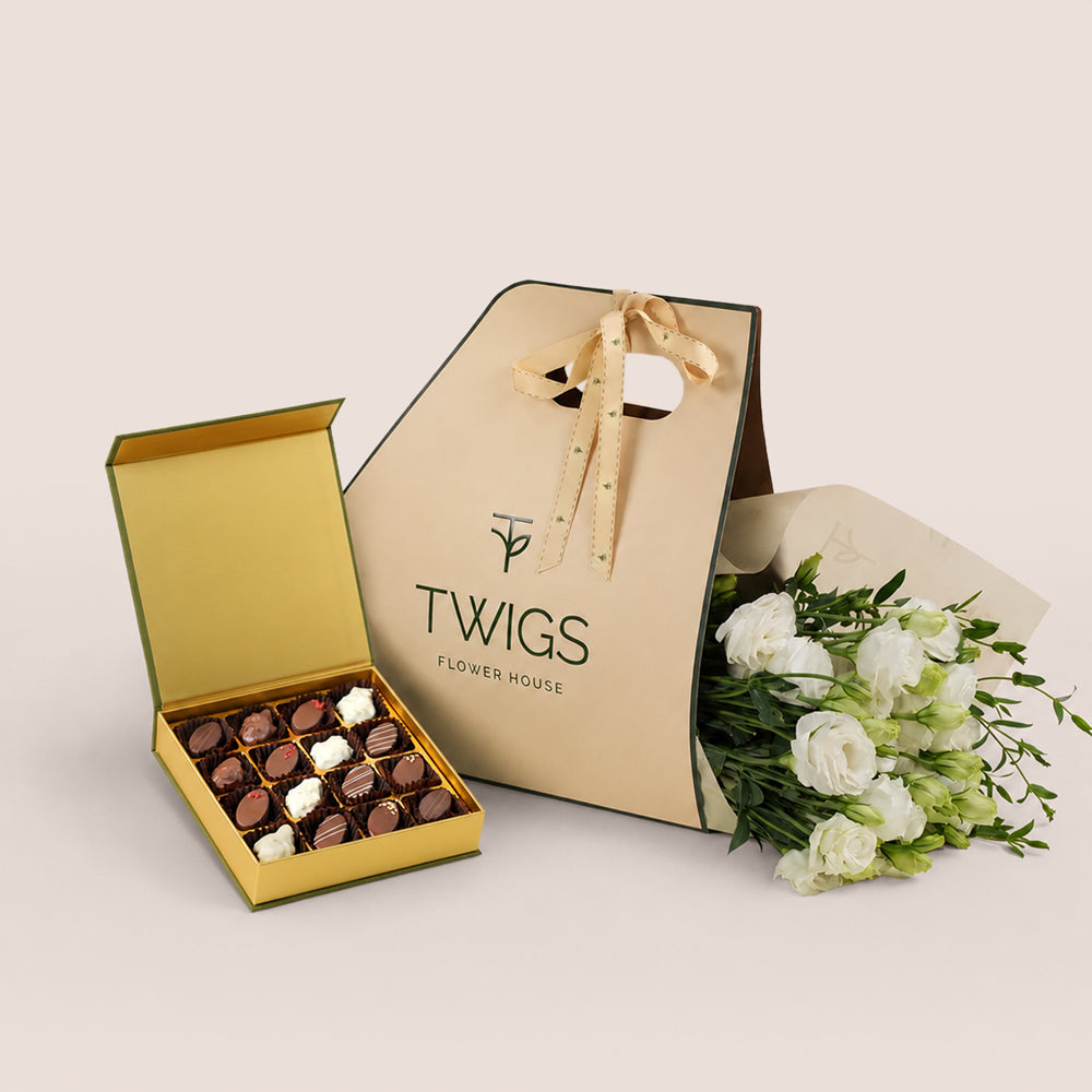 White lisianthus bouquet in TWIGS beige gift bag next to open Bateel Palm date chocolate box, luxury gift bundle Dubai UAE
