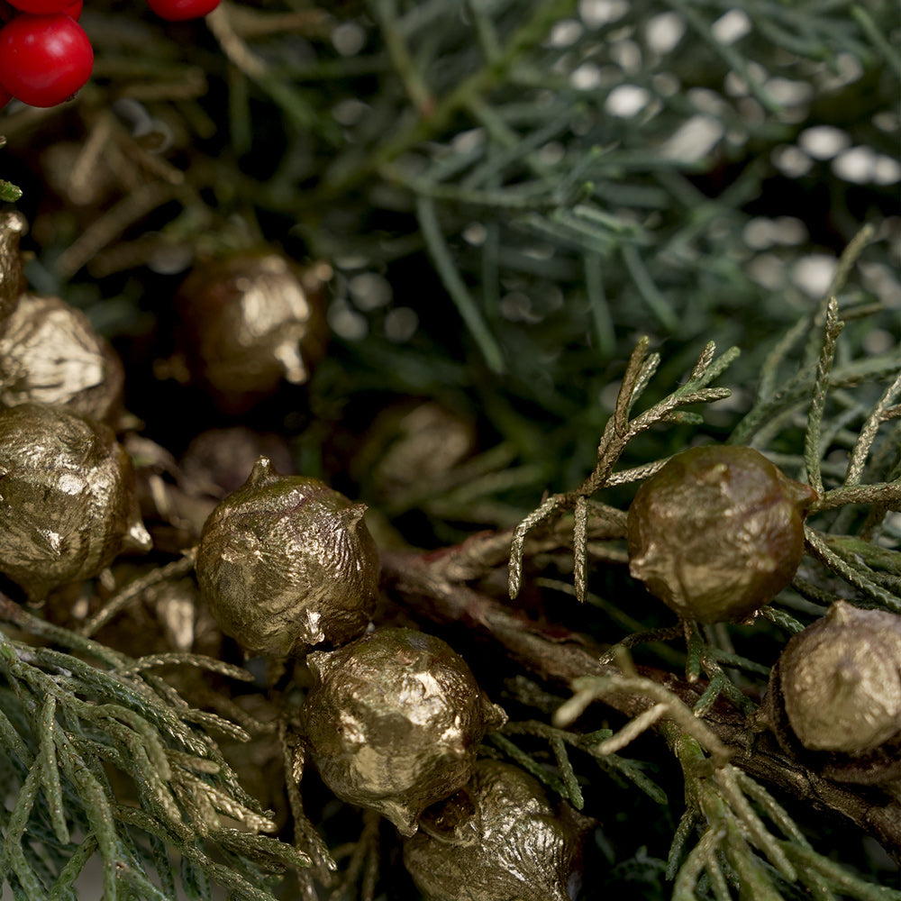 Close-up of gold berries and green foliage with red berries and pine cones in the background