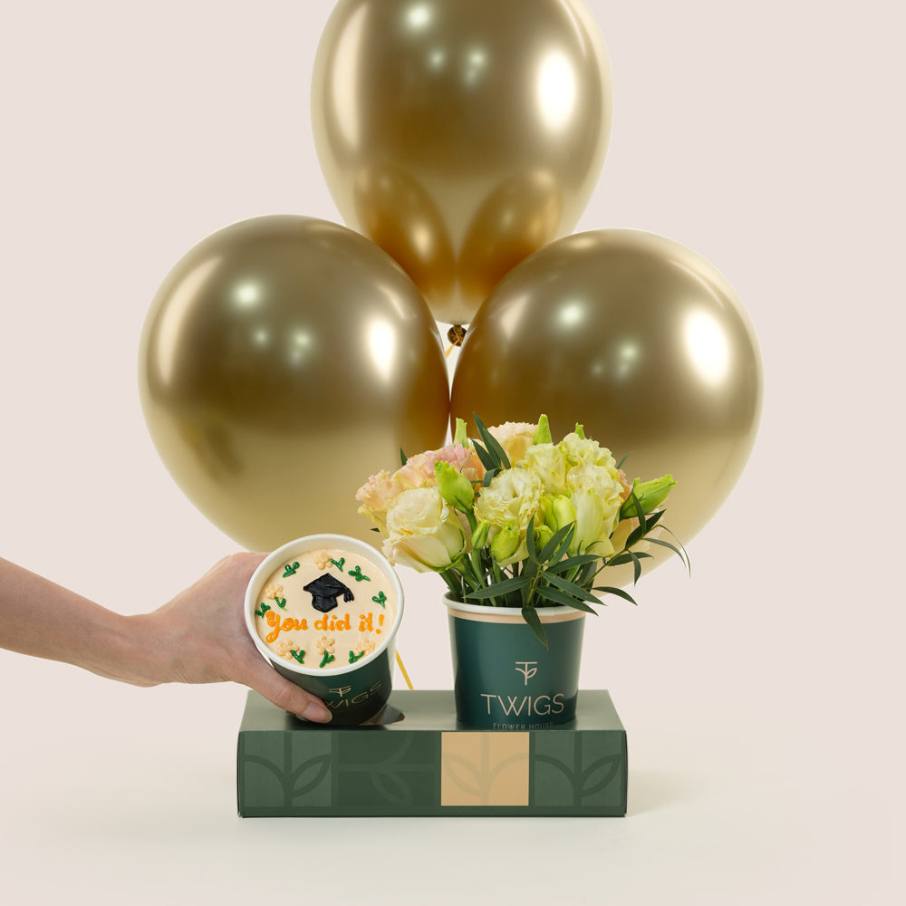 Graduation combo with white flowers in TWIGS cup, chocolate cupcake with "You did it!" topper, and three gold chrome balloons — TWIGS UAE