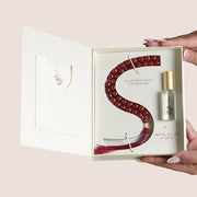 Aqeeq misbaha beads shaped in an S beside Baraka perfume oil bottle in open cream gift box, TWIGS x Light of Sakina collaboration