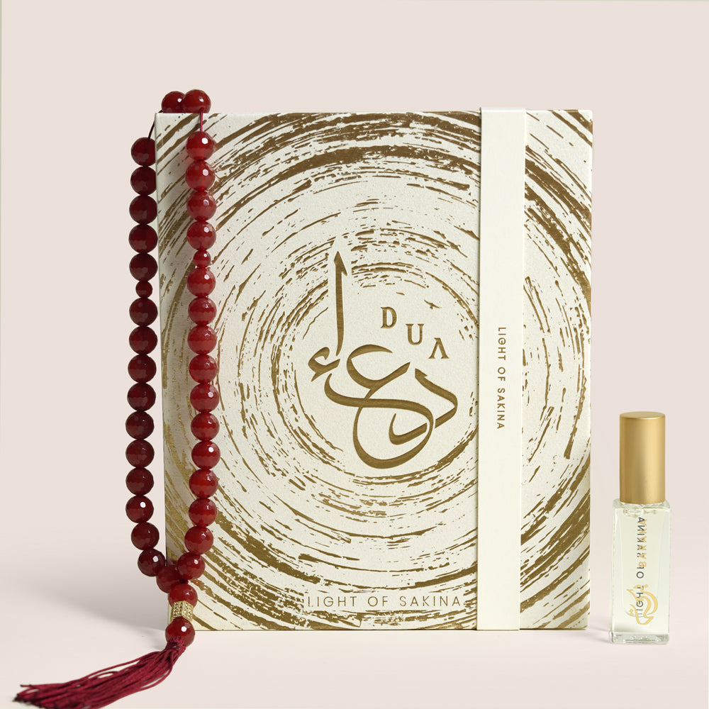 Aqeeq misbaha beads shaped in an S beside Baraka perfume oil bottle in open cream gift box, TWIGS x Light of Sakina collaboration