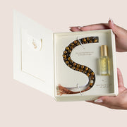 Tiger Eye misbaha beads shaped in an S beside Sakina perfume oil bottle in open cream gift box, TWIGS x Light of Sakina collaboration