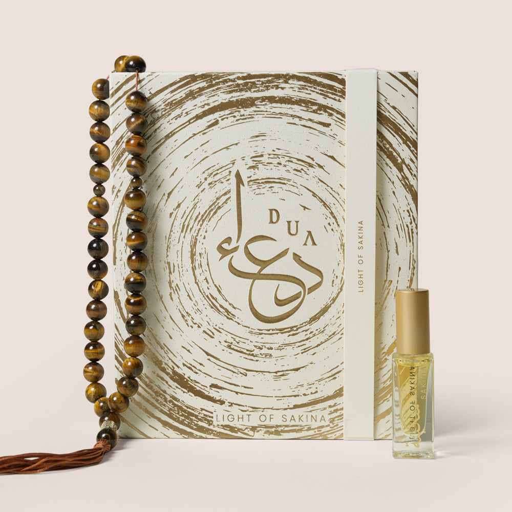 Tiger Eye misbaha beads shaped in an S beside Sakina perfume oil bottle in open cream gift box, TWIGS x Light of Sakina collaboration
