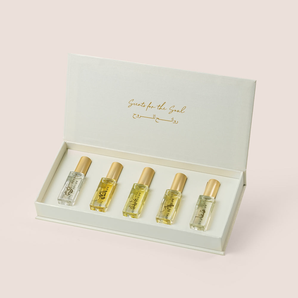 Five Massarah perfume oil bottles in an open beige box beside a gold scent guide card, TWIGS x Light of Sakina collaboration