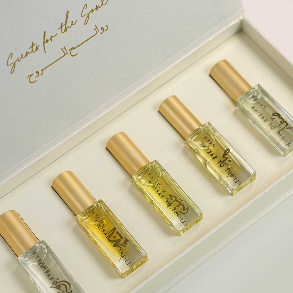 Five Massarah perfume oil bottles in an open beige box beside a gold scent guide card, TWIGS x Light of Sakina collaboration