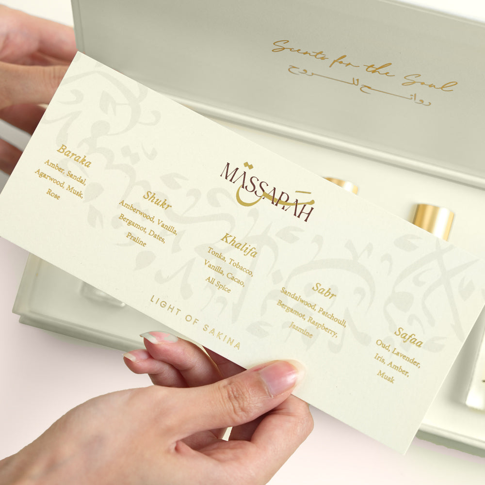 Five Massarah perfume oil bottles in an open beige box beside a gold scent guide card, TWIGS x Light of Sakina collaboration