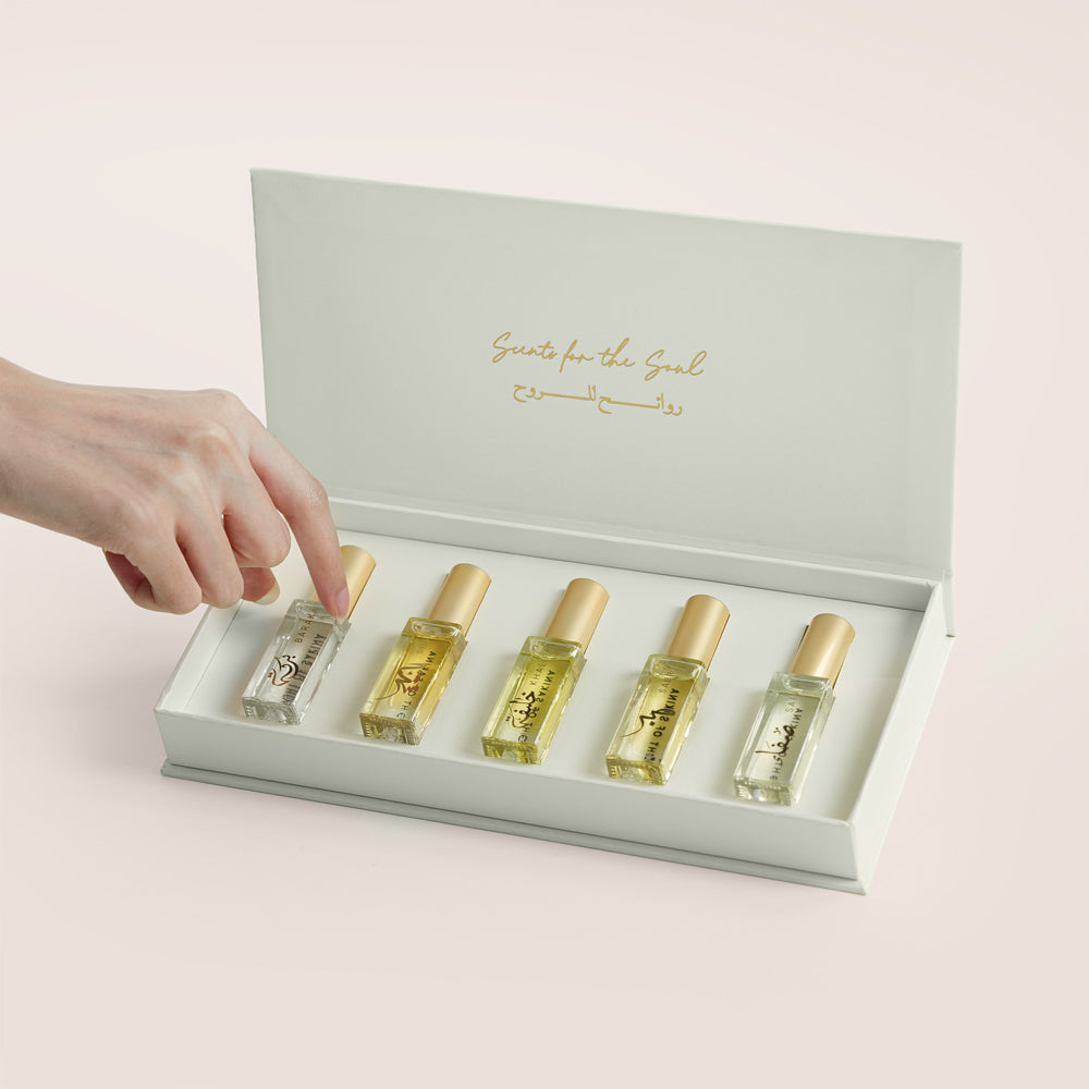 Five Massarah perfume oil bottles in an open beige box beside a gold scent guide card, TWIGS x Light of Sakina collaboration
