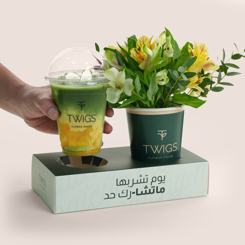 Hand holding a Twigs branded drink cup with a flower arrangement on a matching box.