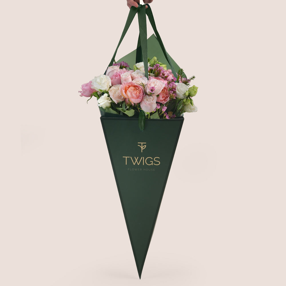 Blushing Bloom Mother’s Day flower arrangement with pink roses in TWIGS cone shaped flower carry bag