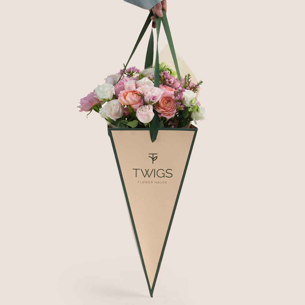 Blushing Bloom Mother’s Day flower arrangement with pink roses in TWIGS cone shaped flower carry bag