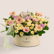 Mother’s Day flower arrangement with peach gerberas, spray roses and pink roses in TWIGS beige round box