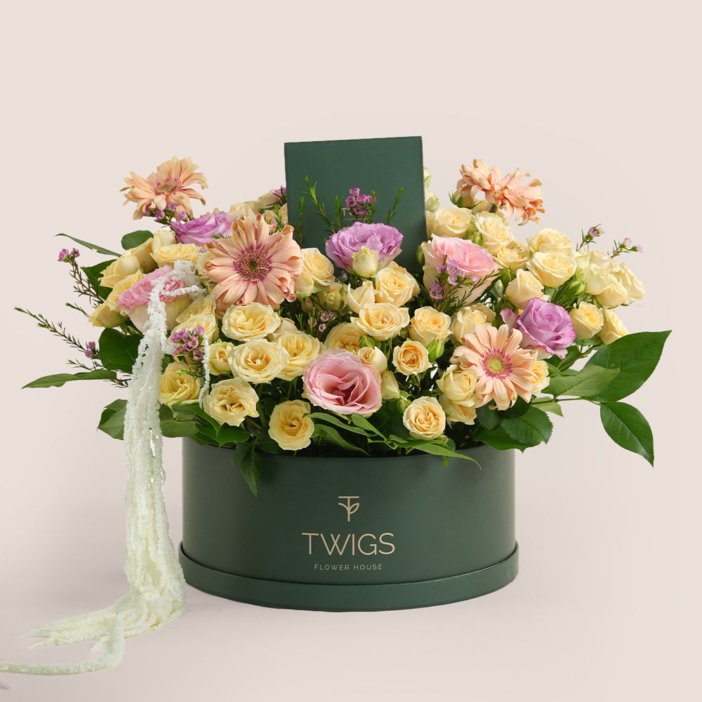 Mother’s Day flower arrangement with peach gerberas, spray roses and pink roses in TWIGS beige round box