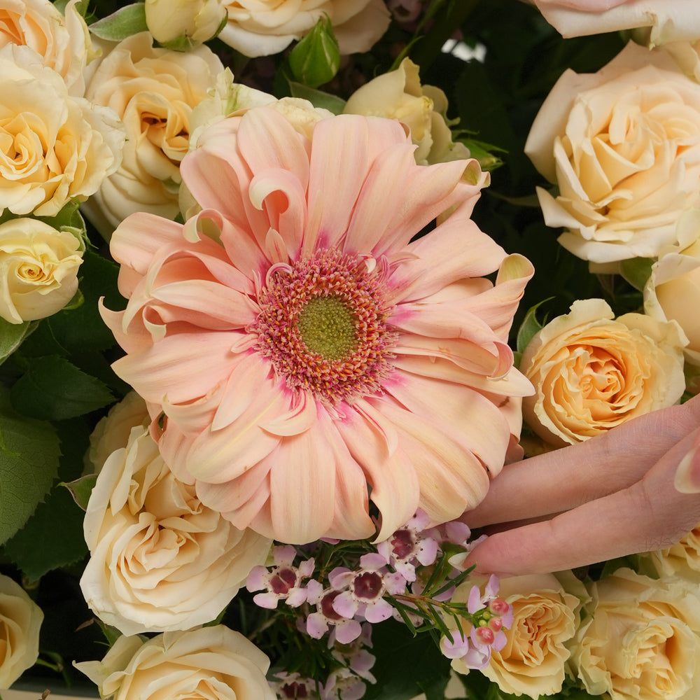 Mother’s Day flower arrangement with peach gerberas, spray roses and pink roses in TWIGS beige round box