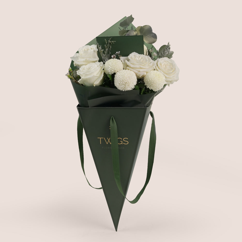 Bouquet of white flowers in a green cone-shaped container with 'TXNGS' branding on a light gray background