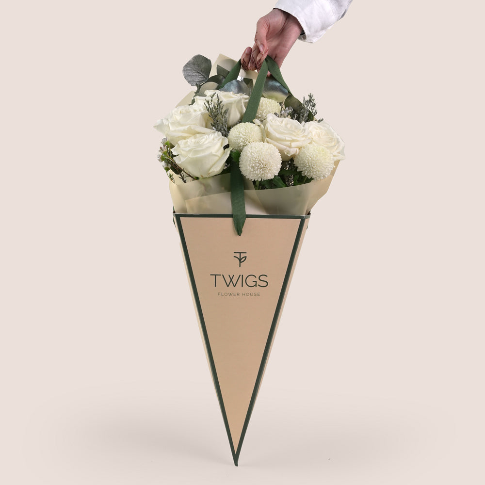 Floral arrangement in a cone-shaped paper holder with 'TWIGS' branding on a light background
