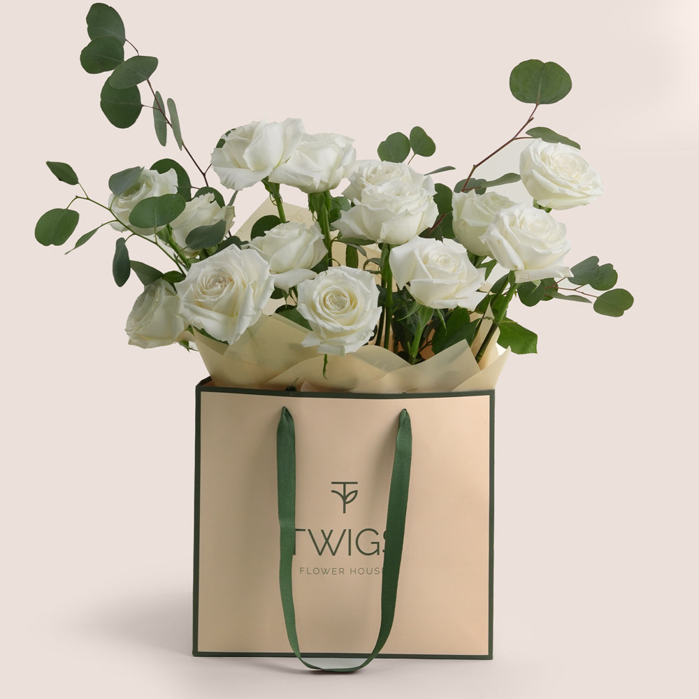 White roses in a Twigs Flower House bag on a light background