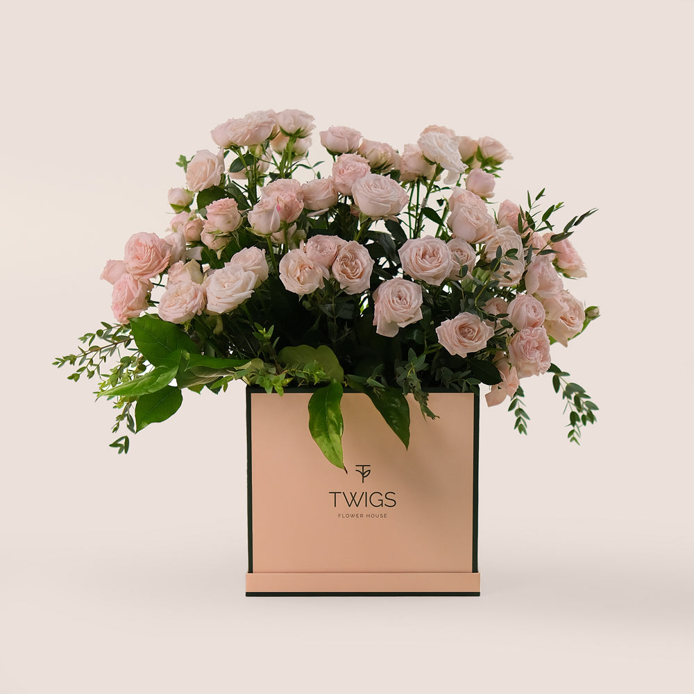 A chic flower box filled with soft pink roses, green leaves arranged to perfection by TWIGS UAE