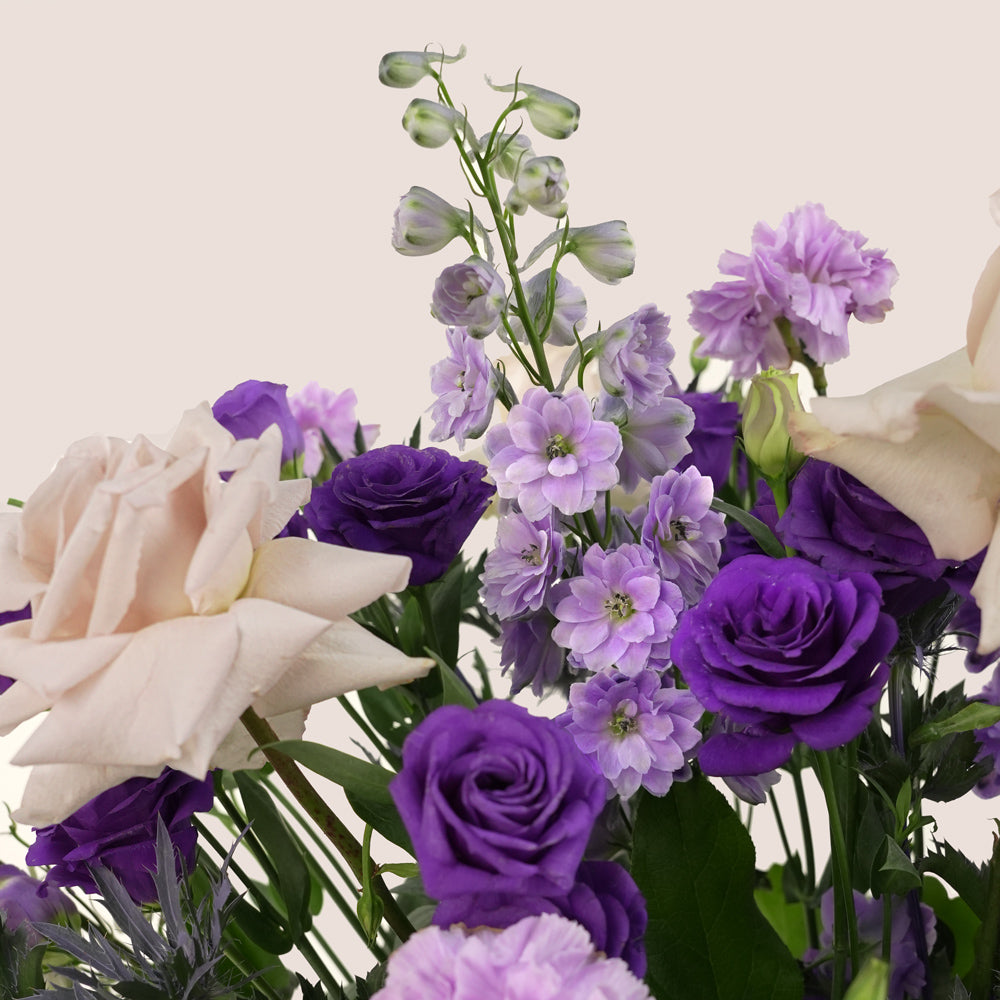 Grande round flower box with quicksand roses, purple lisianthus, carnations, delphiniums, and eryngium in TWIGS beige or green packaging, available for same day flower delivery in Dubai when you buy flowers online.