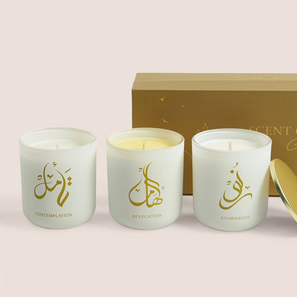 Three white Scent of Medina candles with gold Arabic calligraphy beside gold gift box, TWIGS x Light of Sakina collaboration