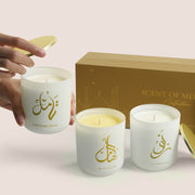 Three white Scent of Medina candles with gold Arabic calligraphy beside gold gift box, TWIGS x Light of Sakina collaboration