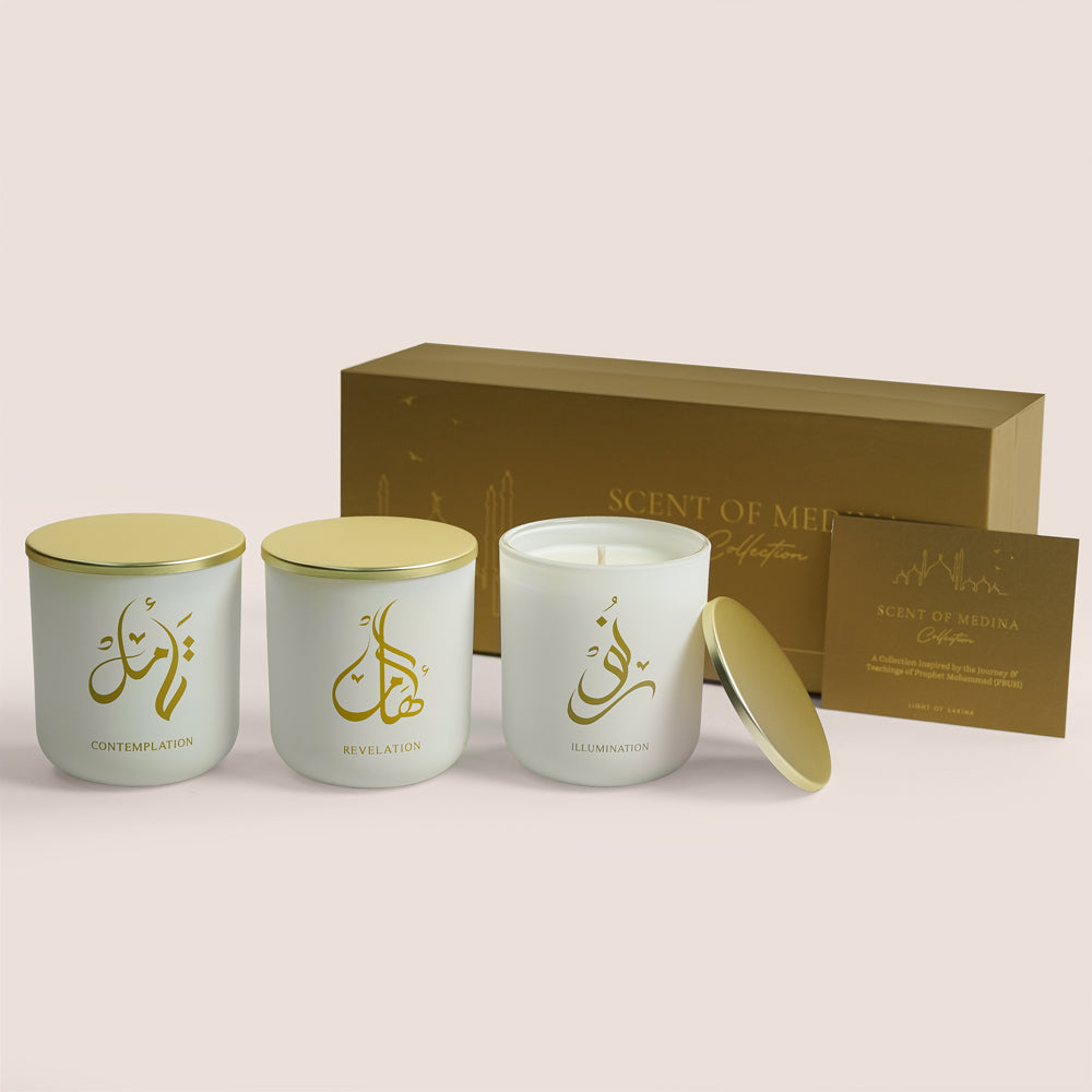 Three white Scent of Medina candles with gold Arabic calligraphy beside gold gift box, TWIGS x Light of Sakina collaboration