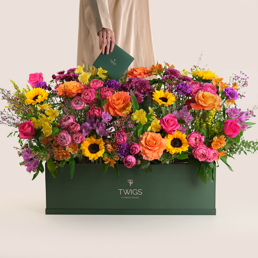 Colorful bouquet of flowers in a green garden box by TWIGS UAE