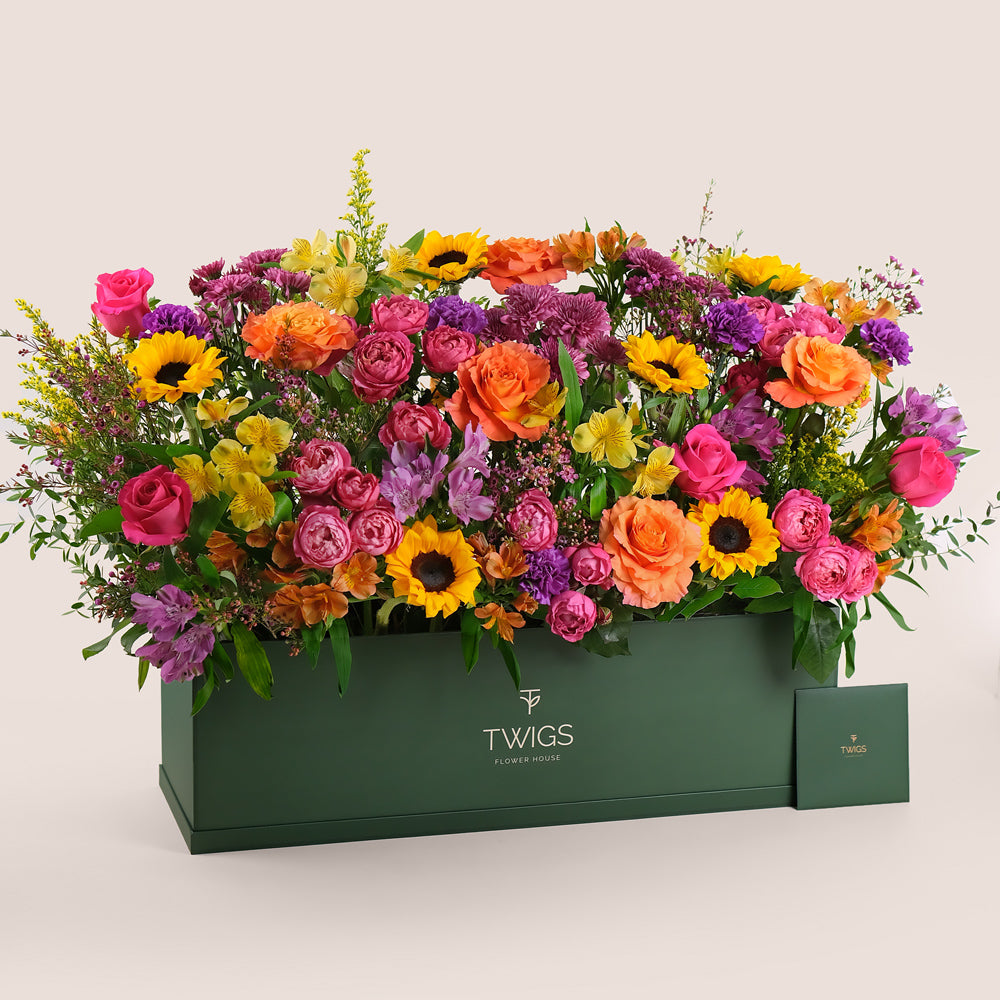 Colorful flower arrangement in a green box with 'TWIGS' 