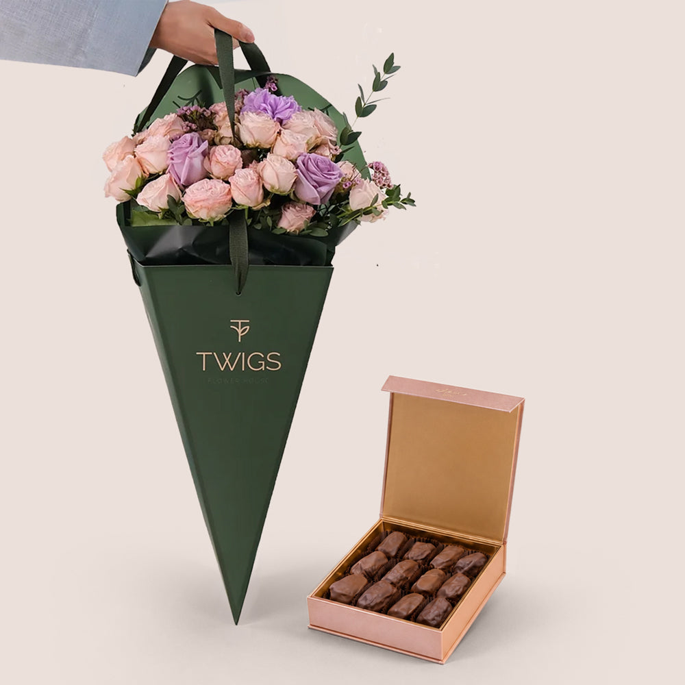 Violet Hues pink and purple rose bouquet in TWIGS cone-shaped bag next to open Bateel Rose Gold date chocolate box, gift bundle Dubai UAE