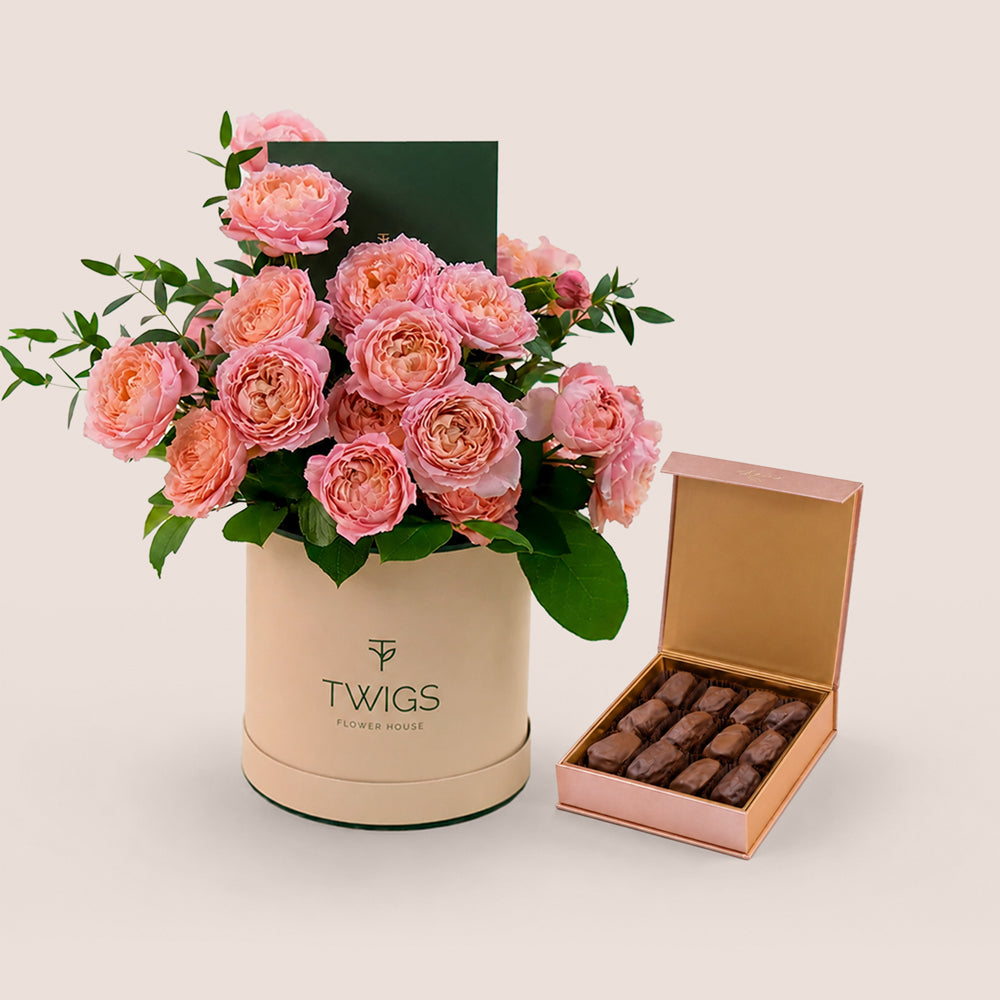 TWIGS Juliet bundle — pink garden roses in beige deluxe round box next to open Bateel Rose Gold date chocolate box, Dubai UAE